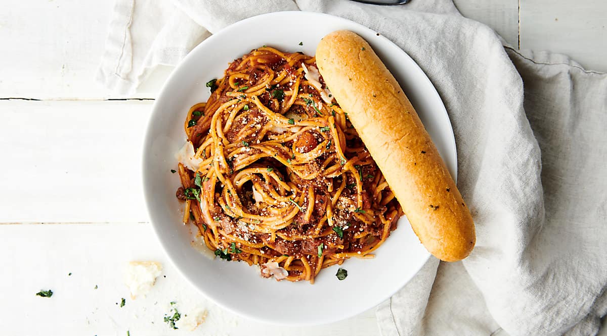 plate of spaghetti with breadstick above