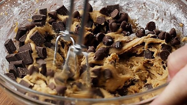 Chocolate chips being mixed into cookie dough
