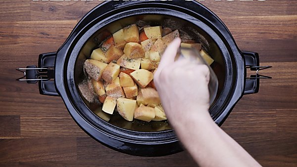 veggies in crockpot being sprinkled with spices