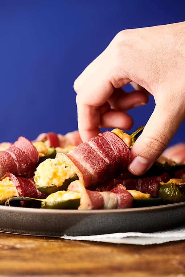 lifting jalapeno poppers on a plate