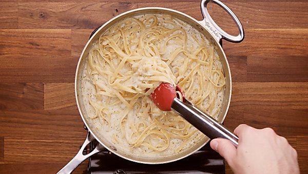 Finished one pot fettuccine alfredo being taken out of pot with tongs