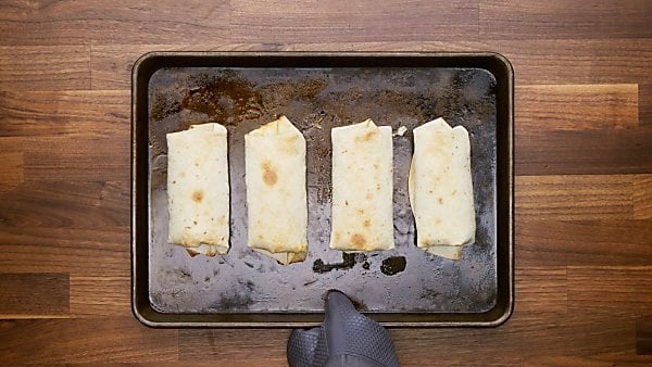 Baked breakfast burritos on baking sheet