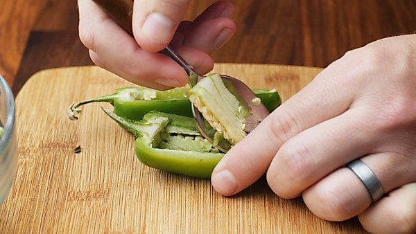 Jalapeno half being scraped with a spoon
