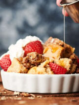 French toast casserole with strawberries and whipped cream and maple syrup drizzled