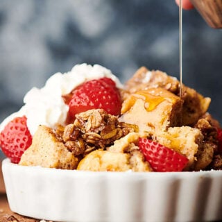 French toast casserole with strawberries and whipped cream and maple syrup drizzled