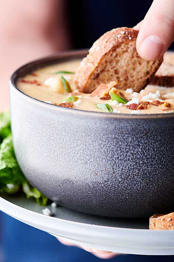 Slice of bread being dipped into bowl of soup