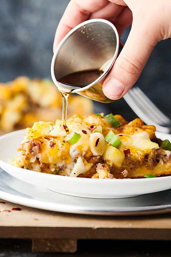 Maple syrup being drizzled over slice of maple sausage breakfast pizza