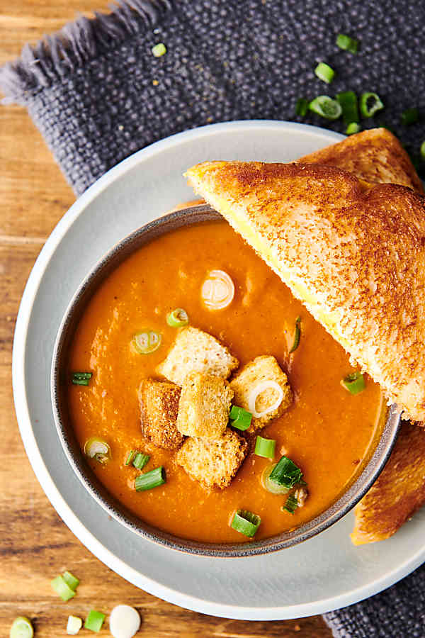Overhead of roasted tomato soup on a plate with grilled cheese