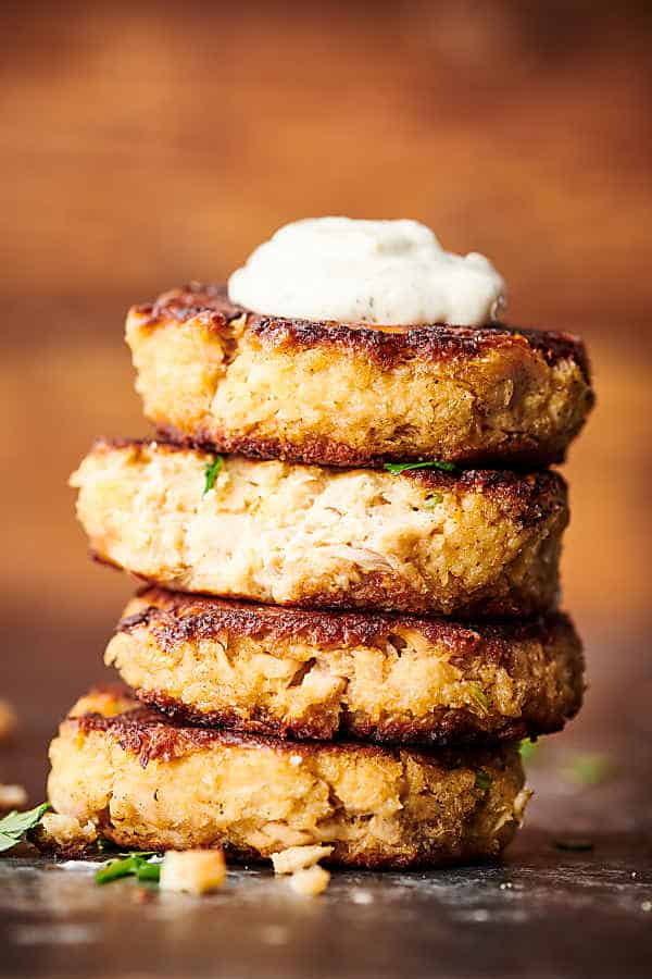 Four salmon patties stacked with a dollop of tartar sauce on top