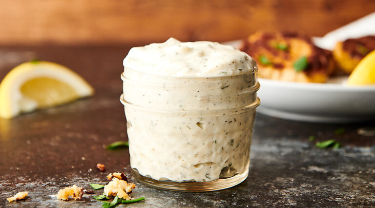 Jar of tartar sauce with salmon patties in the background