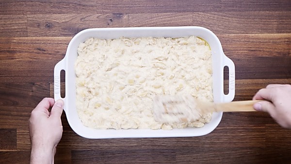 Crab mac and cheese being spread into baking dish
