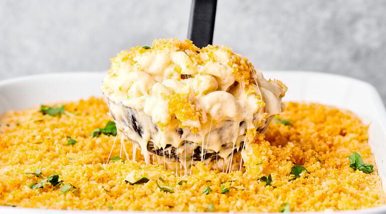 Ladle of baked mac and cheese being lifted out of baking dish