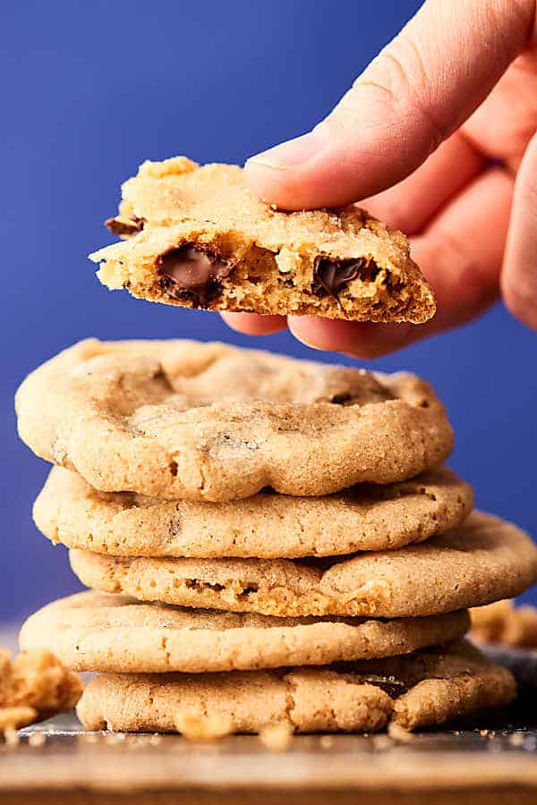 Stacked chocolate chip cookies, one with bite out held