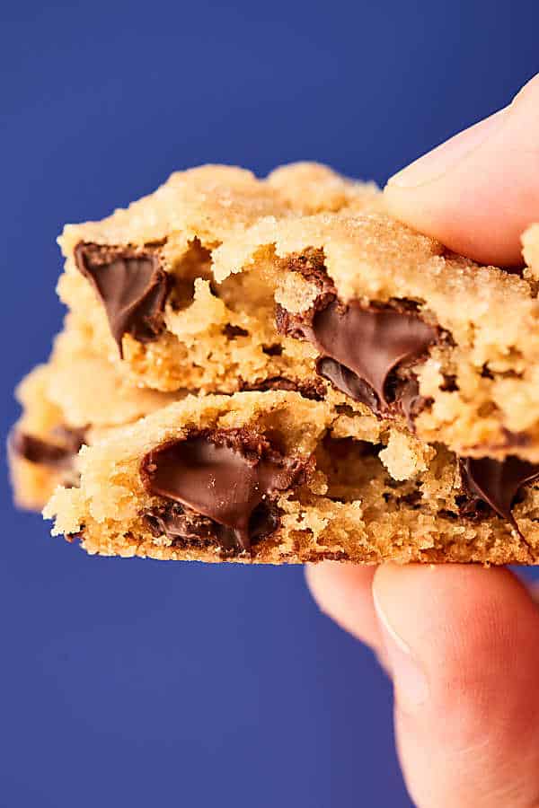 2 chocolate chip cookies with bites out, stacked, held