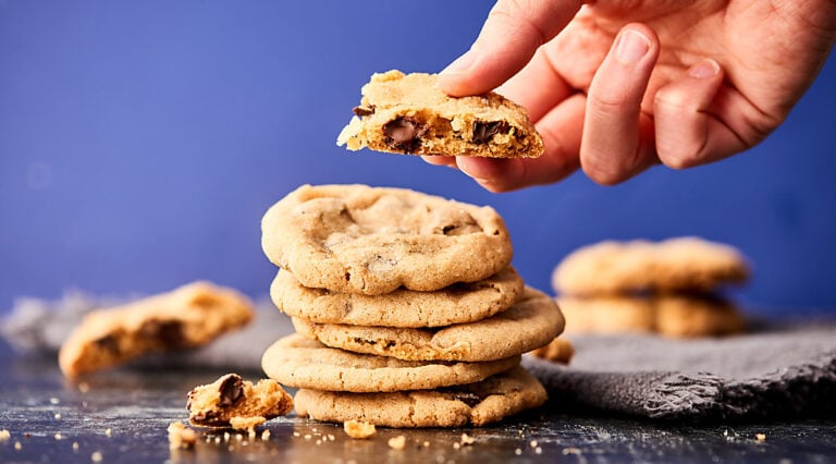 Stack of the best chocolate chip cookies, one with bite taken out held