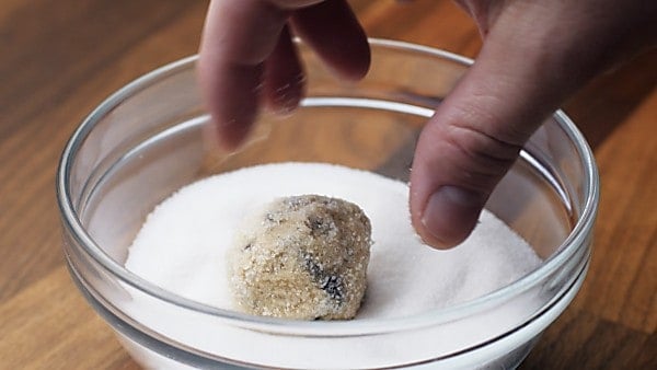 Cookie dough ball being coated in sugar