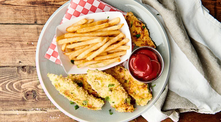 Chicken tenders on plate with fries and ketchup above