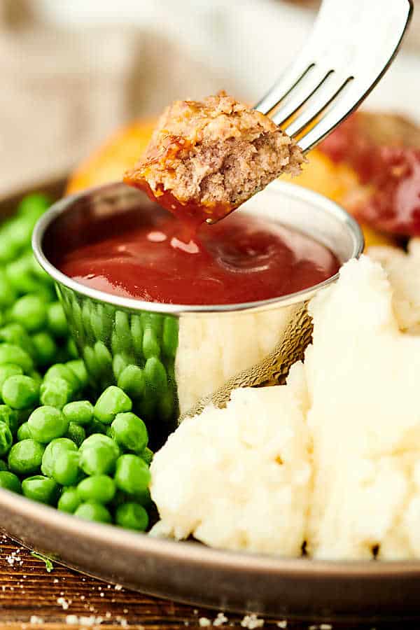 Piece of meatloaf being dipped into ketchup