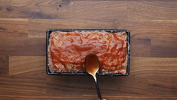 Meatloaf topping being spread on uncooked meatloaf