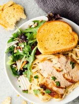 plate of chicken alfredo with side salad and garlic bread above