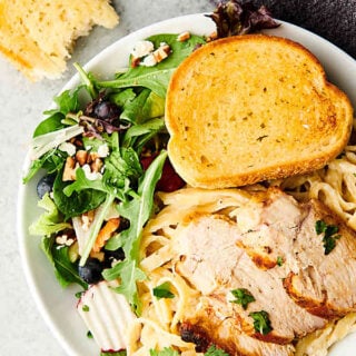 plate of chicken alfredo with side salad and garlic bread above