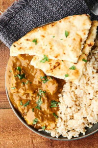 Chicken curry on a plate with naan and rice above