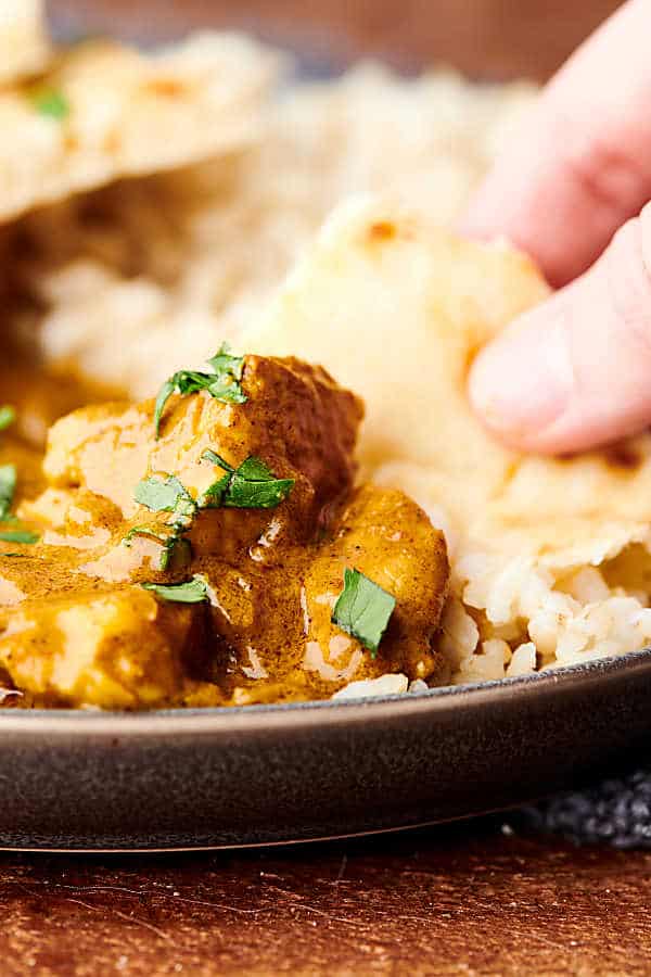 Naan being dipped into chicken curry