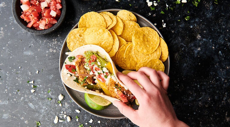 chicken fajita being set on plate with tortilla chips above