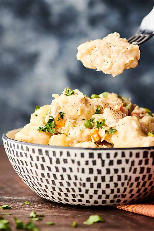 spoonful being taken out of bowl of chicken and dumplings