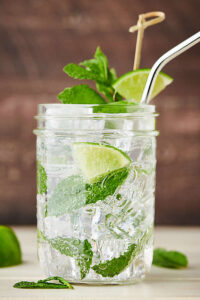 mojito in a jar with lime, mint, and straw side view
