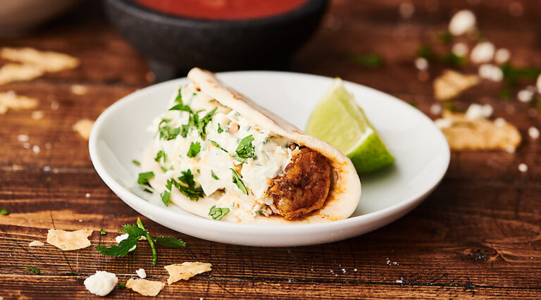 Shrimp taco on a plate with lime wedge