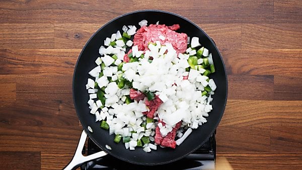 uncooked beef and veggies in skillet
