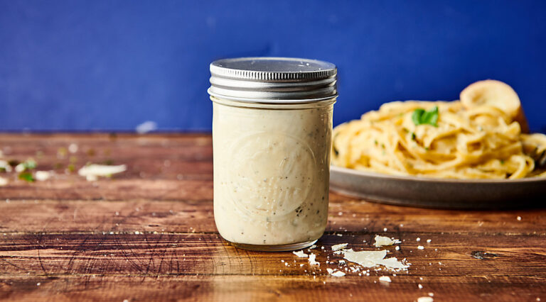 jar of alfredo sauce, plate of pasta in background