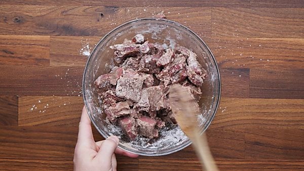 cubed beef mixed with flour in mixing bowl