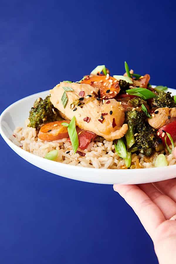 plate of chicken stir fry held blue background