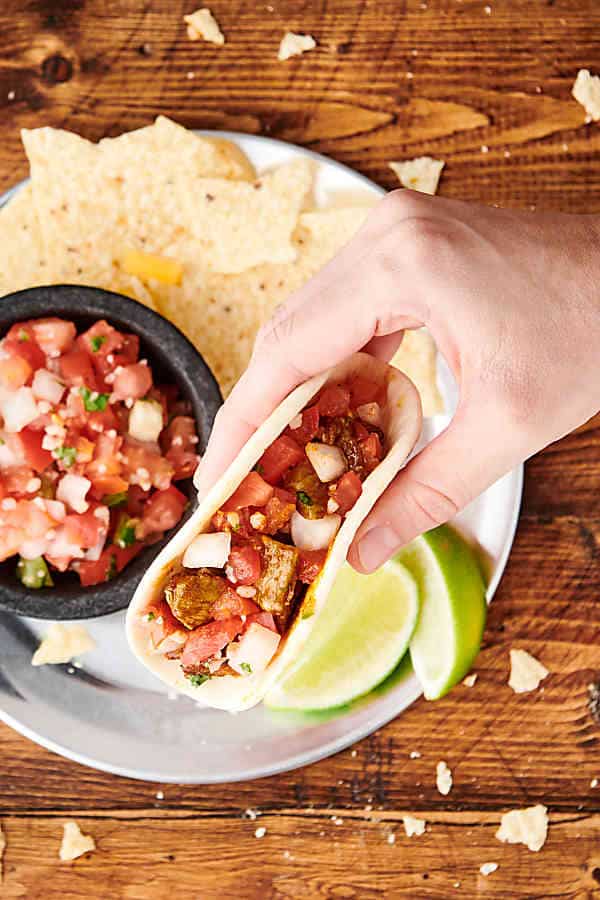 chicken taco being lifted off plate above