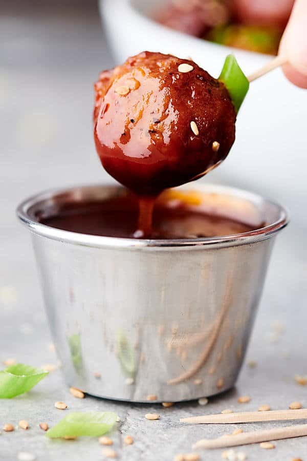 meatball being dipped into sauce