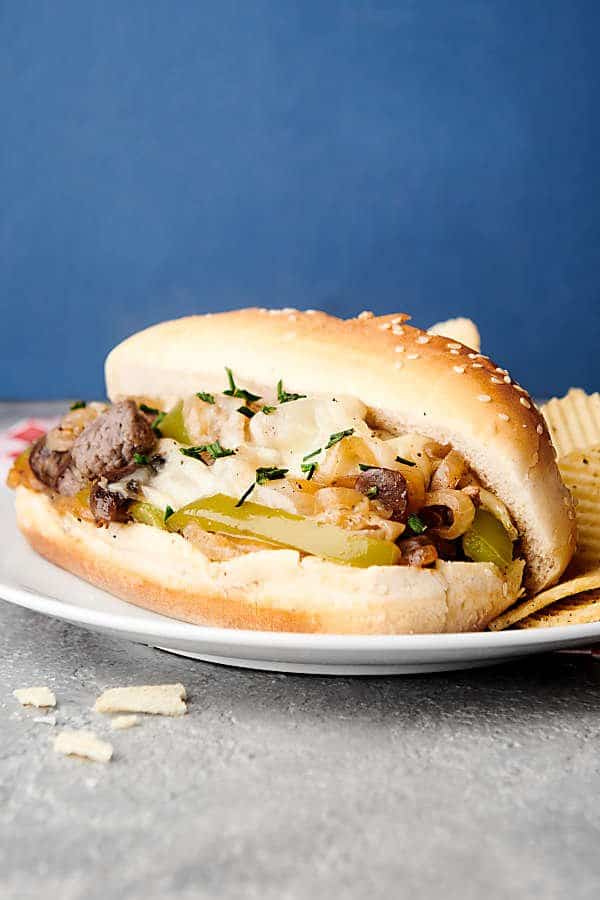 philly cheesesteak sandwich on plate with chips
