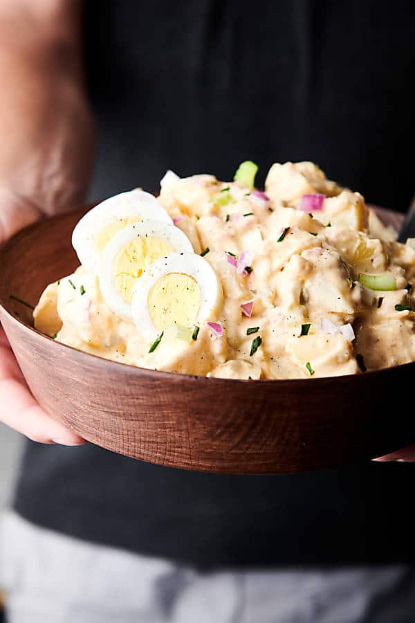 bowl of potato salad held two hands