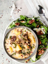 bowl of zuppa toscana on plate with salad above