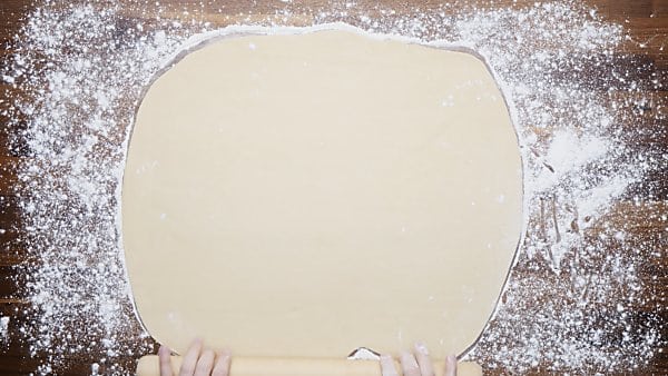 dough being rolled out on floured surface