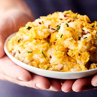 plate of hashbrown casserole held two hands