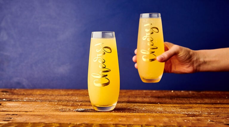 two mimosa glasses, one being picked up