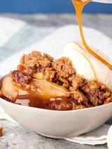caramel being drizzled over bowl of apple crumble with scoop of ice cream