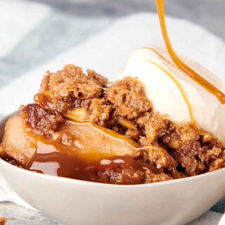 caramel being drizzled over bowl of apple crumble with scoop of ice cream