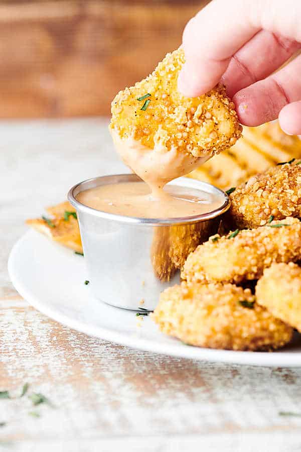 chicken nugget being dipped into chick fil a sauce