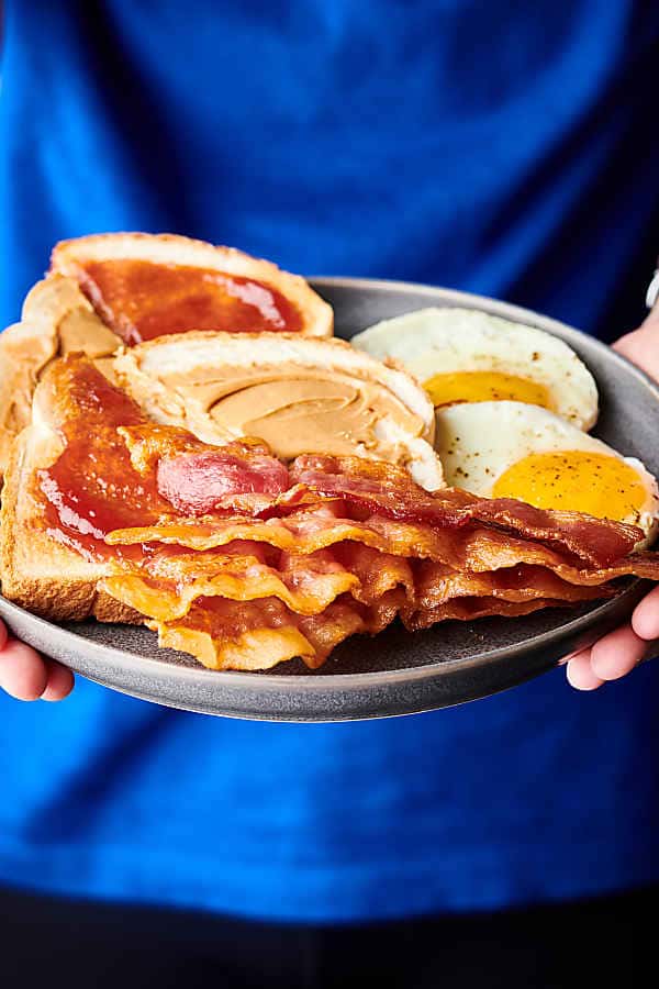 plate with bacon, eggs, and toast held