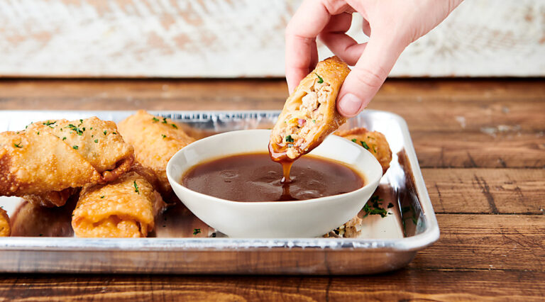 egg roll being dipped in soy sauce