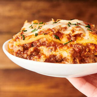 lasagna on a plate held in one hand