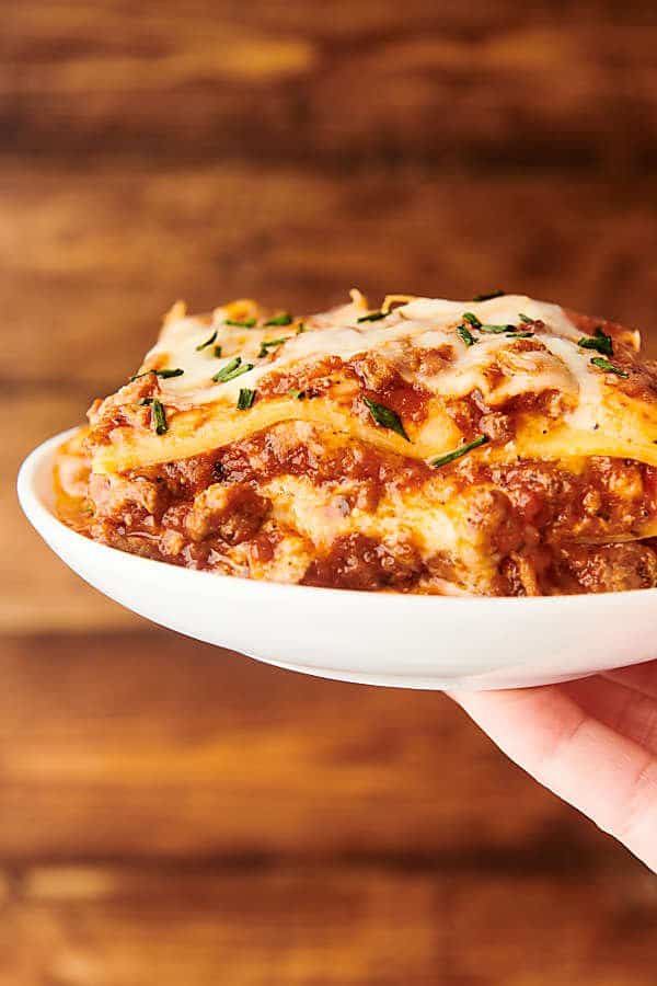 lasagna on a plate held in one hand